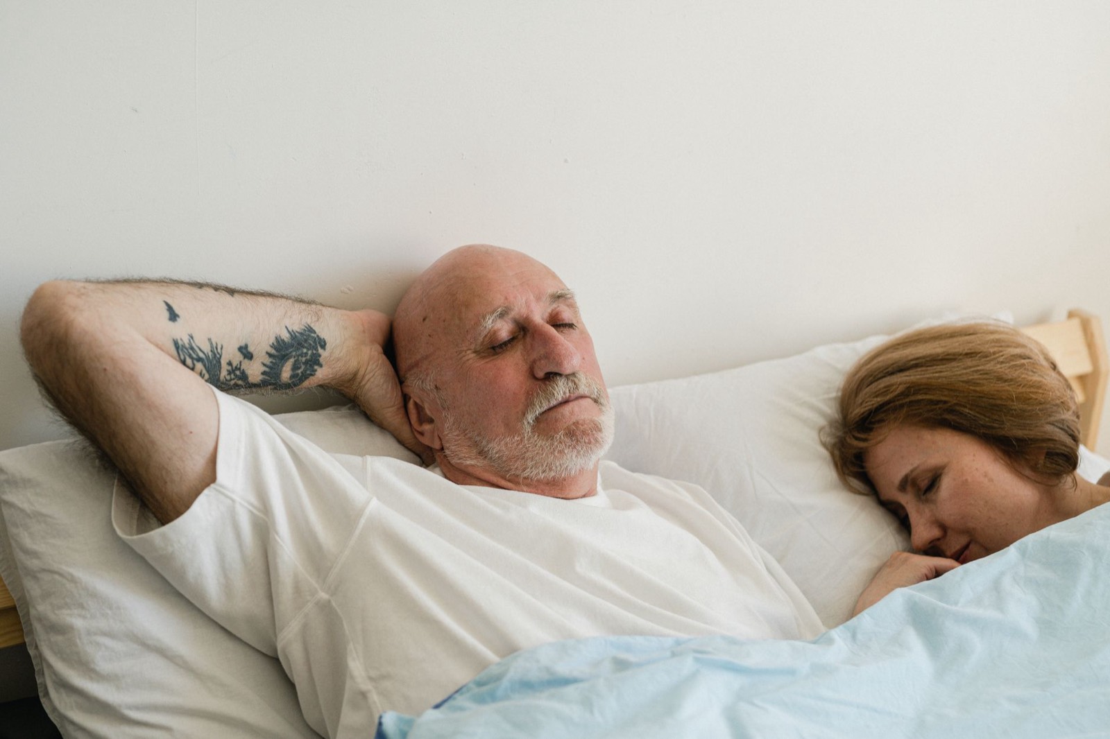Couple endormi dans un grand lit, chacun de son côté du matelas
